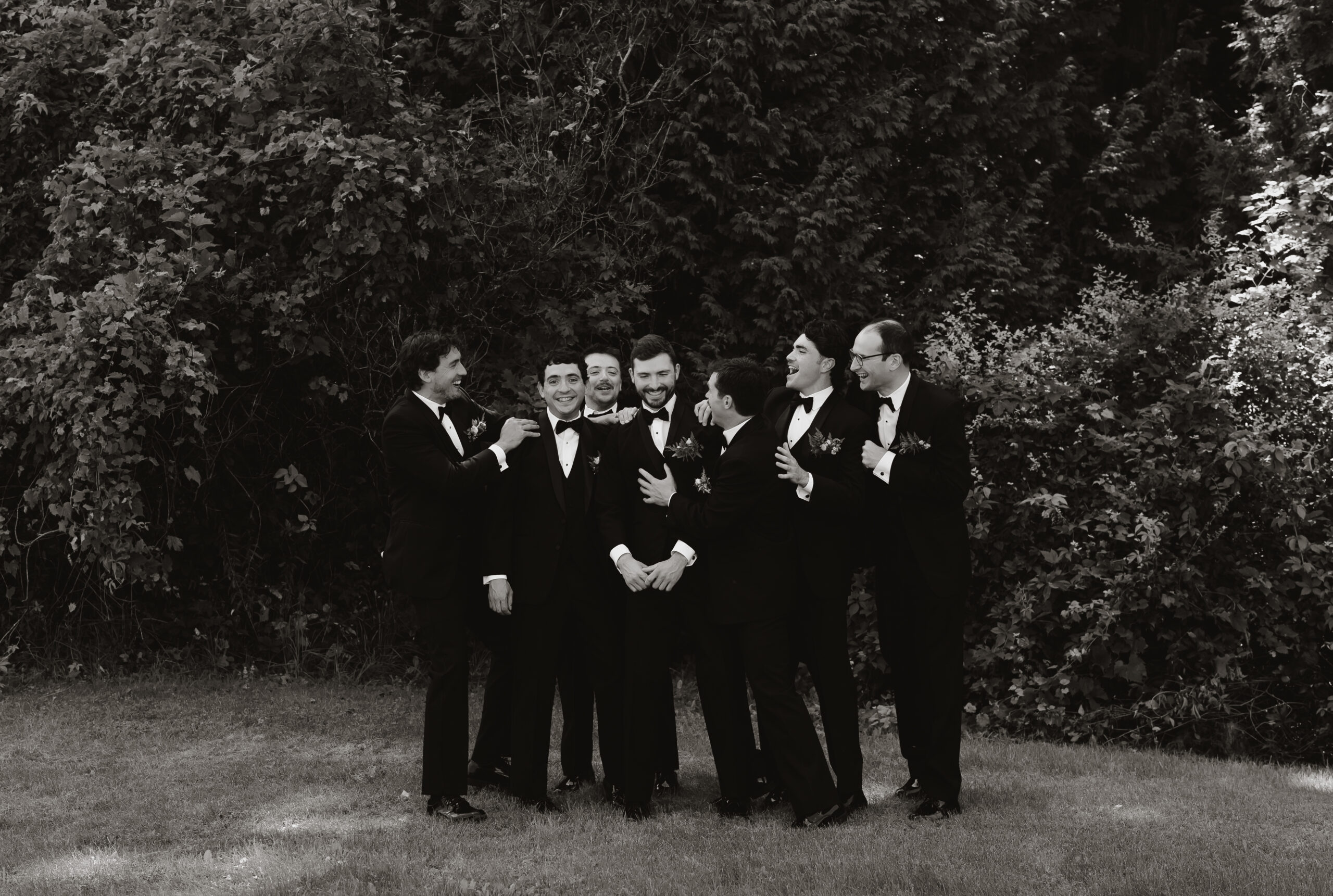 High-quality wedding photo of a groom and groomsmen laughing together on the wedding day in New England. This candid moment highlights the value of professional wedding photography and explains why photographers charge what they’re worth.