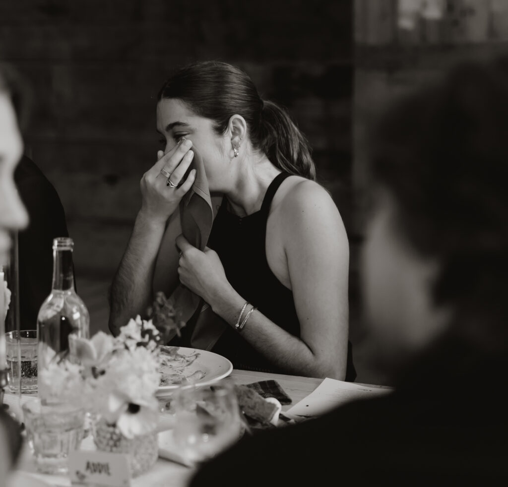Candid portrait of a guest wiping their happy tears during the speeches at the wedding reception.