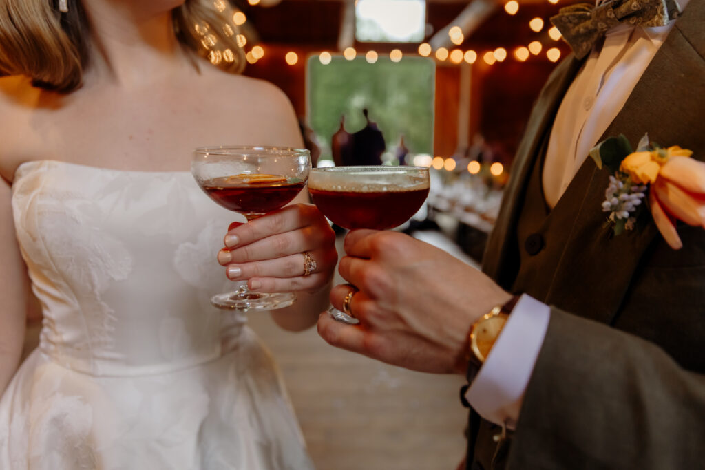 A photo of the bride and groom cheers-ing their espresso martinis at their reception.
