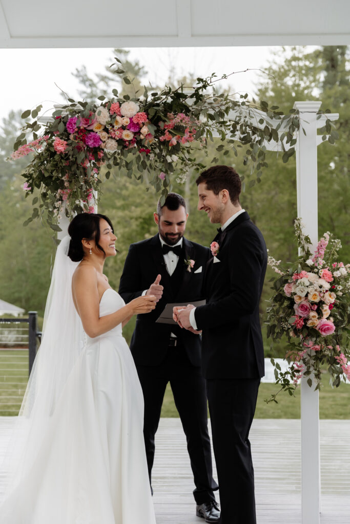 Bride and groom standing together at the altar during their Beautiful Rainy Wedding Day in Vermont. The outdoor wedding ceremony at the Essex Resort and Spa is the perfect Vermont wedding venue.