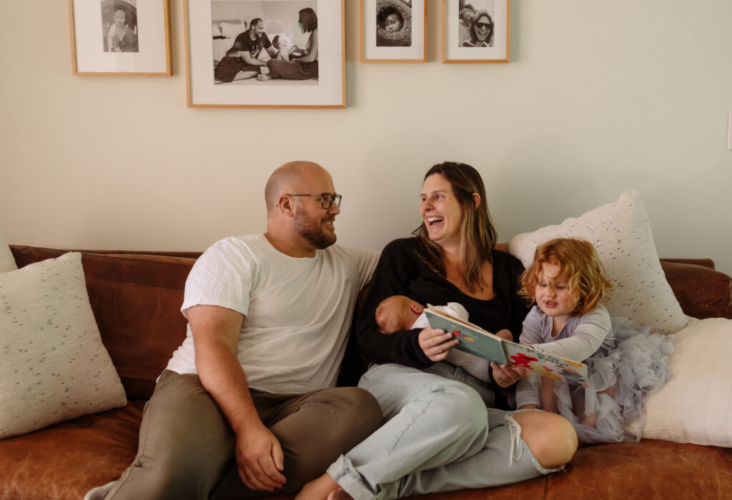 Candid family photos at home in Maine with children snuggling and reading with parents and newborn sibling.