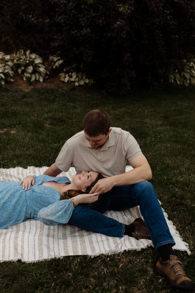 Whimsical golden hour portraits in a New England as the couple lays in the grass on a blanket together.
