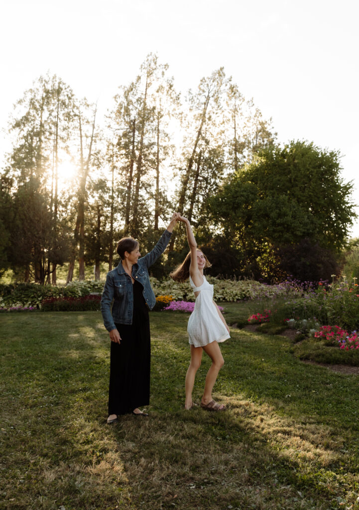Maine senior photoshoot in wildflower field, girl in floral dress, natural and relaxed posing with sunlight glowing photo with her mom