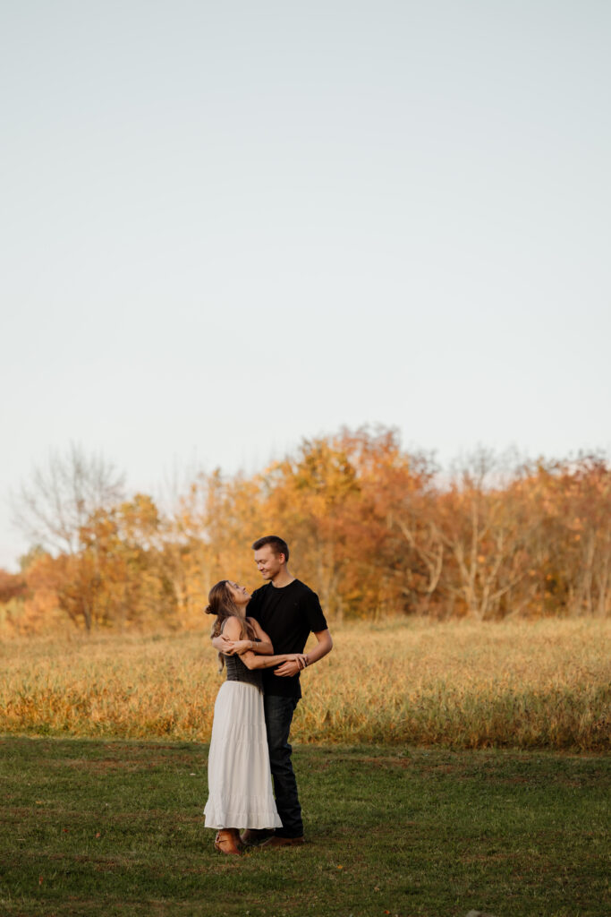Engaged couple dancing through a field of autumn grass Maine engagement photos