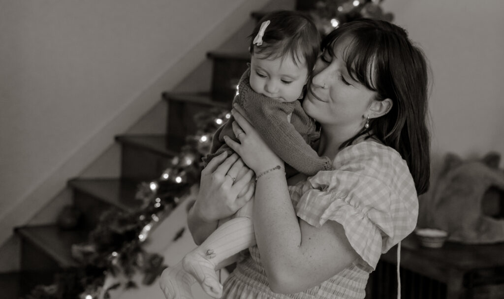Mother and daughter hugging as the mother holds her during an in-home session in Maine.
