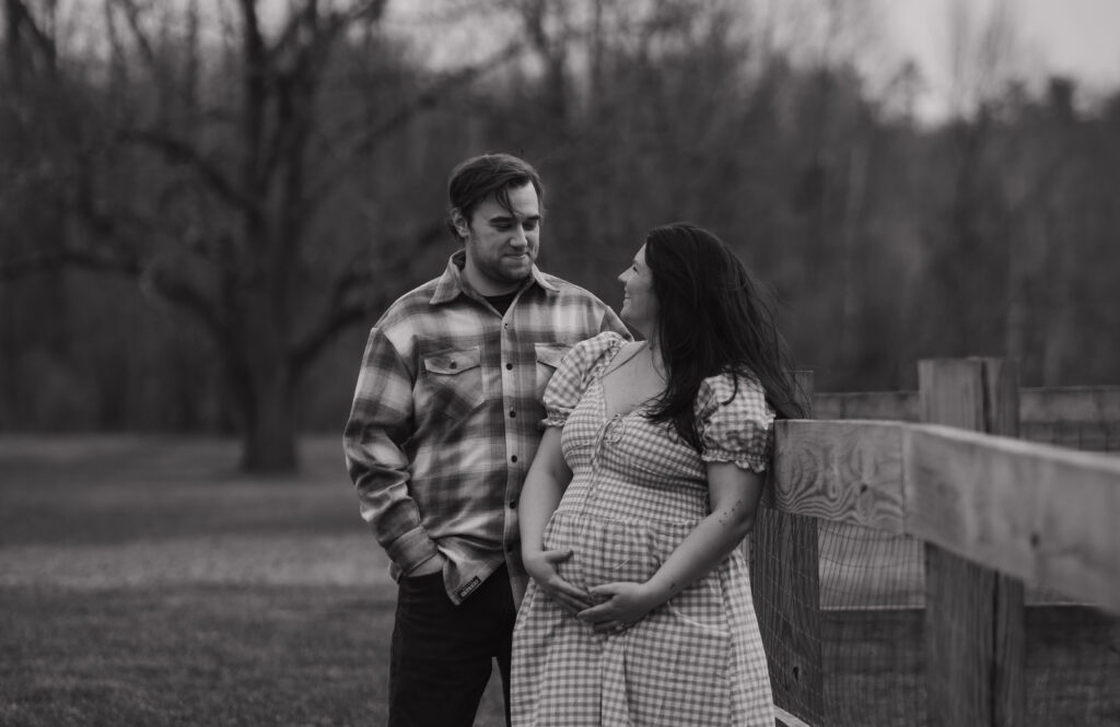 Black-and-white outdoor maternity portrait of pregnant woman with husband in Maine