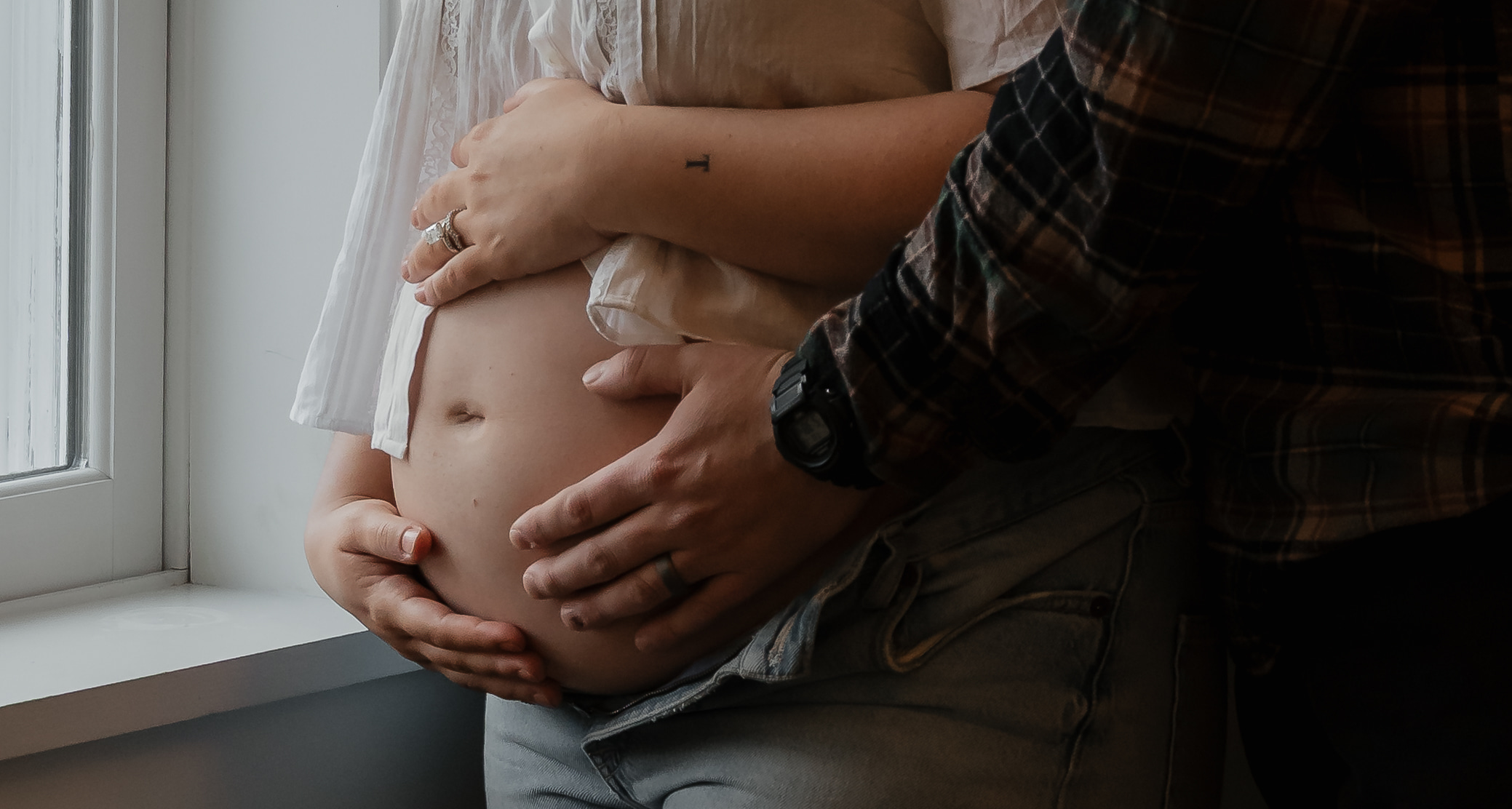 Close-up of pregnant belly with both parents' hands during intimate Maine maternity session