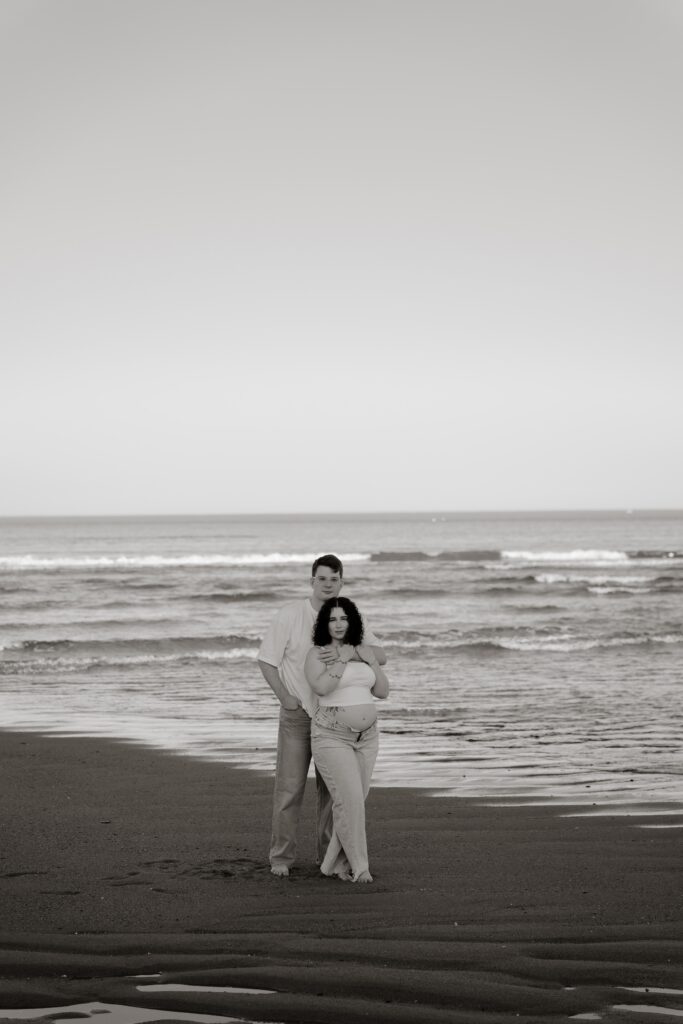 Maternity photography session on a beach in Coastal Maine with a pregnant mother and partner by the ocean