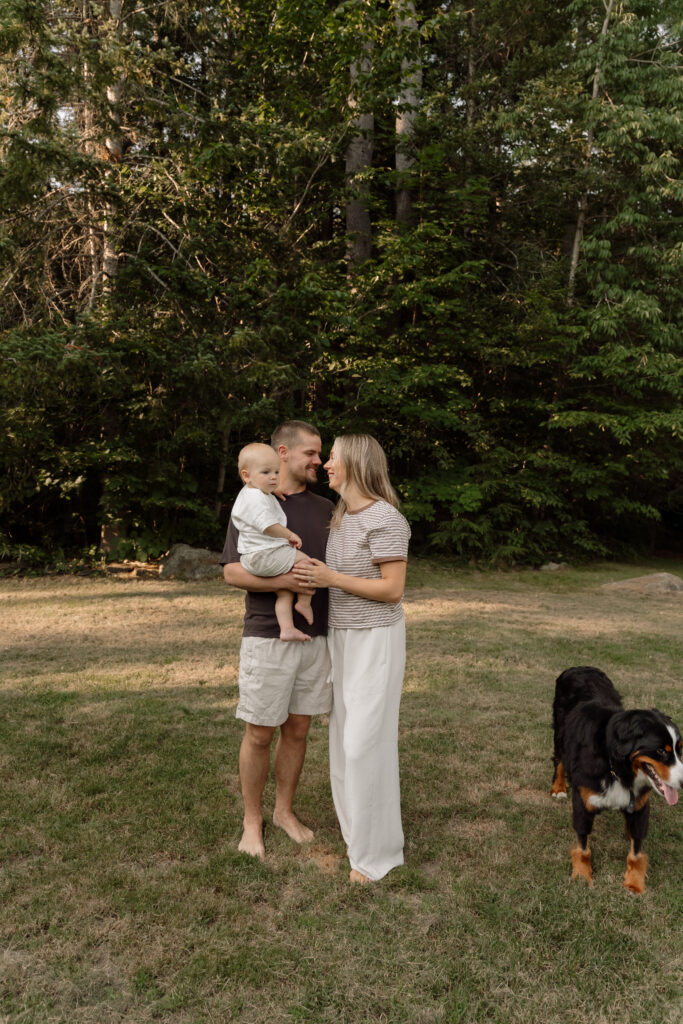 Parents hold their baby nose to nose during an in-home newborn session with their dog in Maine